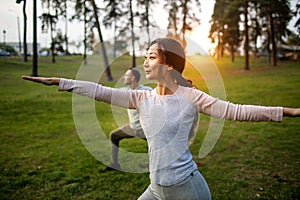 Young Couple Doing Yoga In Park Together at sunset.