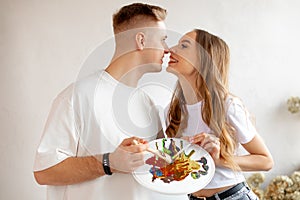 Young couple drawing together. Woman and man kissing and holding brush and pallette with colors.