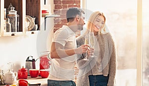 Young couple drinking champagne and smiling in the kitchen