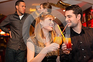 Young couple drinking cocktails in ba