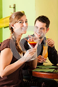 Young couple drinking cocktails in bar