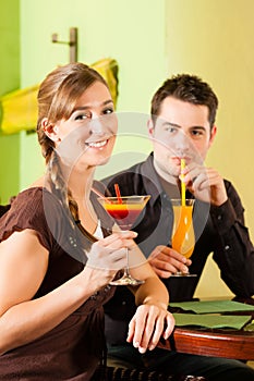 Young couple drinking cocktails in bar