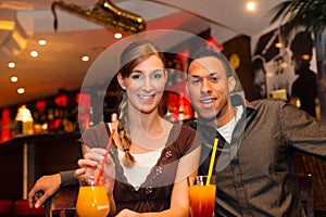 Young couple drinking cocktails in bar