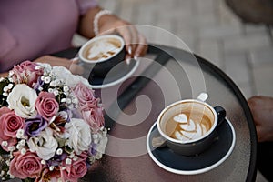 Young couple is drinking cofee. Two cups of cofee standing on the cofee table alongside with the flower pot closeup