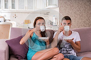 Young Couple Drinking Coffee on Sofa at Home