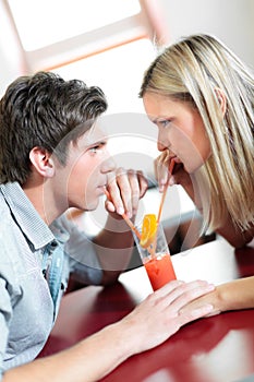 Young couple drinking one coctail