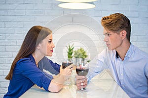 Young couple drinking red wine and flirting in kitchen at home.