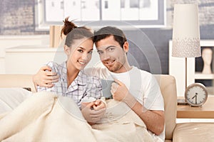 Young couple drinking tea in bed smiling happily