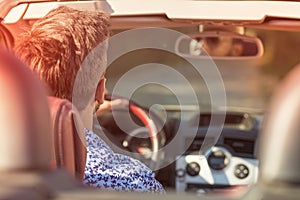 Young Couple Driving Along Country Road In Open Top Car