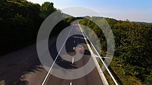 Young Couple Driving Along Country Road In Open Top Conertible Car. Aerial shot.