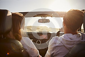 Young couple driving with sunroof open, rear passenger POV