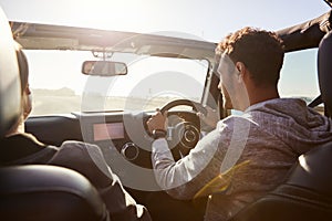 Young couple driving with sunroof open, rear passenger POV