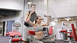 Young couple with dumbbells flexing muscles in gym