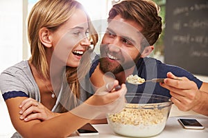 Young Couple Eating Breakfast In Kitchen Together