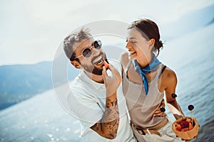 Couple eating fruit on the beach- summer party with friends and healthy food concept