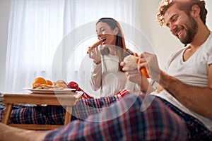 A young couple eating a tasty food for a breakfast in the bed. Love, relationship, together