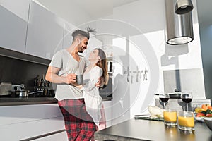 Young Couple Embrace In Kitchen, Hispanic Man And Asian Woman Hug Morning Breakfast