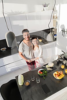 Young Couple Embrace In Kitchen, Hispanic Man And Asian Woman Hug Top Angle View