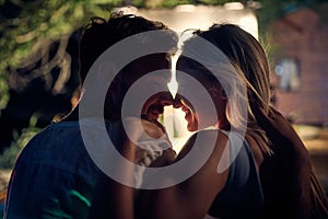 Young couple in embrace at outdoor movie night. Close up portrait shot of young man and woman in close hug feeling happy. Holiday