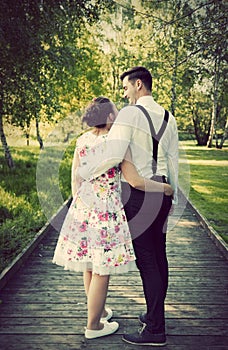 Young couple embrace while standing on wooden path