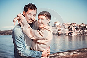 Young couple embraces on the shore of Lake Bracciano.