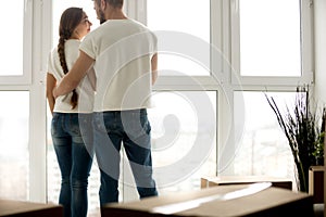 Young couple embracing in new apartment with packed belongings