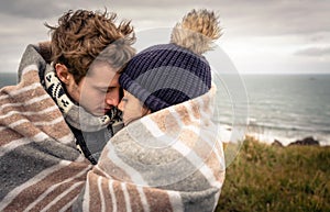 Young couple embracing outdoors under blanket in a