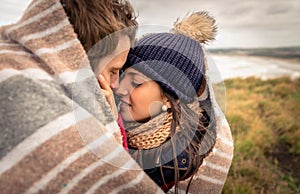 Young couple embracing outdoors under blanket in a