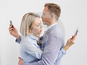 Young couple embracing and still using their mobile phones