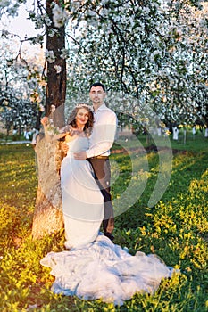 Young couple embracing at sunset in blooming spring garden. Love and romantic theme.