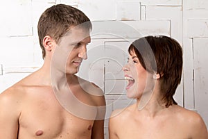 Young couple with emotions of giggle near the white wall