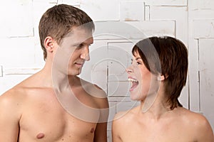 Young couple with emotions of giggle near the white wall photo
