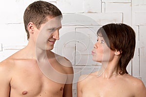 Young couple with emotions of suddenness near the white wall