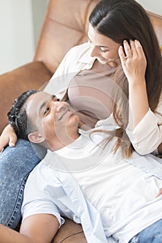 Young couple enjoy time at home watching tv on the sofa - happy girl and boy in relationship indoor with love and relationship -