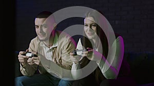 Young couple enjoy videogame together at home. Family in living room playing games console when sitting on couch. Funny