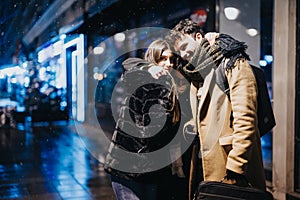 Young couple enjoying a cozy winter evening in the city snowfall.