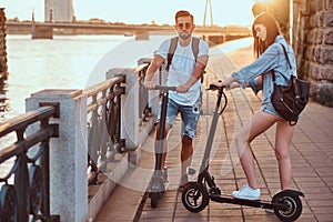 Young couple is enjoying electro scooter`s riding