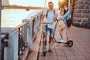 Young couple is enjoying electro scooter`s riding