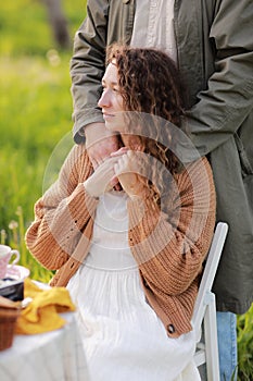 Young couple enjoying food and drinks in beautiful summer green park on romantic date picnic, handsome man and woman