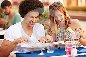 Young Couple Enjoying Meal In Outdoor Restaurant