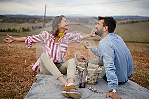 A young couple is enjoying moments of hedonism with grapes and wine on the picnic on a large meadow. Relationship, together, love