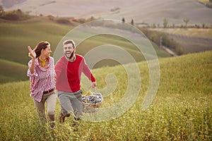 A young couple is enjoying nature while running a large meadow by holding hands. Relationship, love, together, picnic, nature