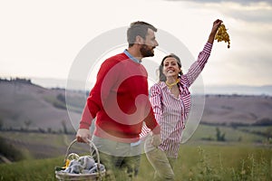 A young couple enjoying nature while walking a large meadow. Relationship, love, together, picnic