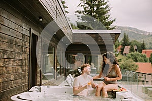 Young couple enjoying in outdoor hot tub on vacation