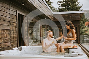 Young couple enjoying in outdoor hot tub on vacation