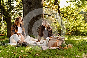 Young couple enjoying picnic time while sitting under the tree in park