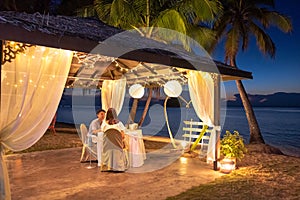 Young couple enjoying a romantic dinner by the tropical beach