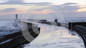 Young couple enjoying sunset at breakwater pier with lighthouse.