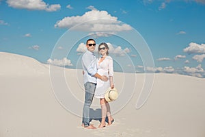 Young couple enjoying the sunset in the dunes. Romantic traveler walks in the desert. Adventure travel lifestyle concept