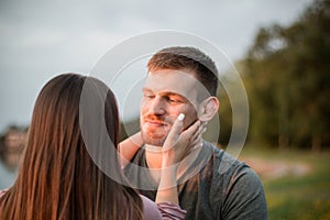 Young couple enjoying the sunset by the lake. Man gazing at his girlfriend